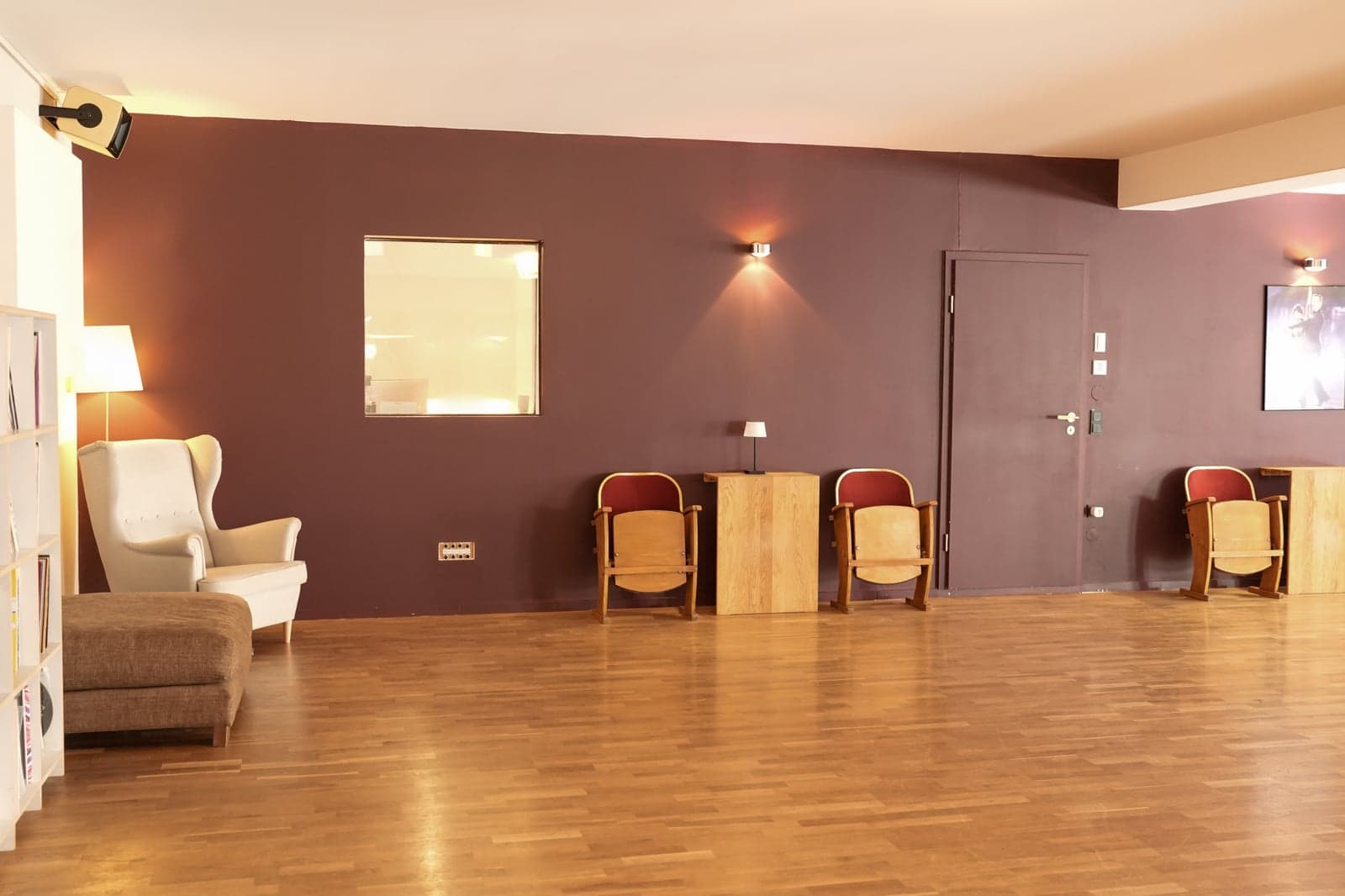Sessel und kleine Holztische an der warm beleuchteten Wand im Motus Studio